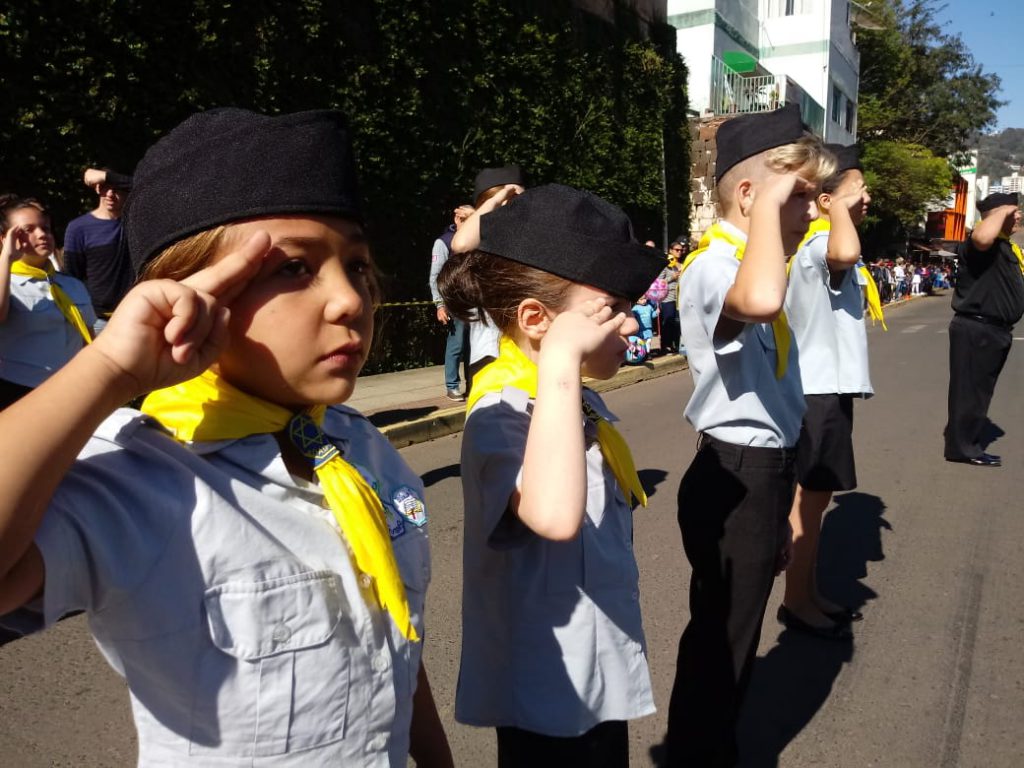 Crianças prestam continência a bandeira nacional. 